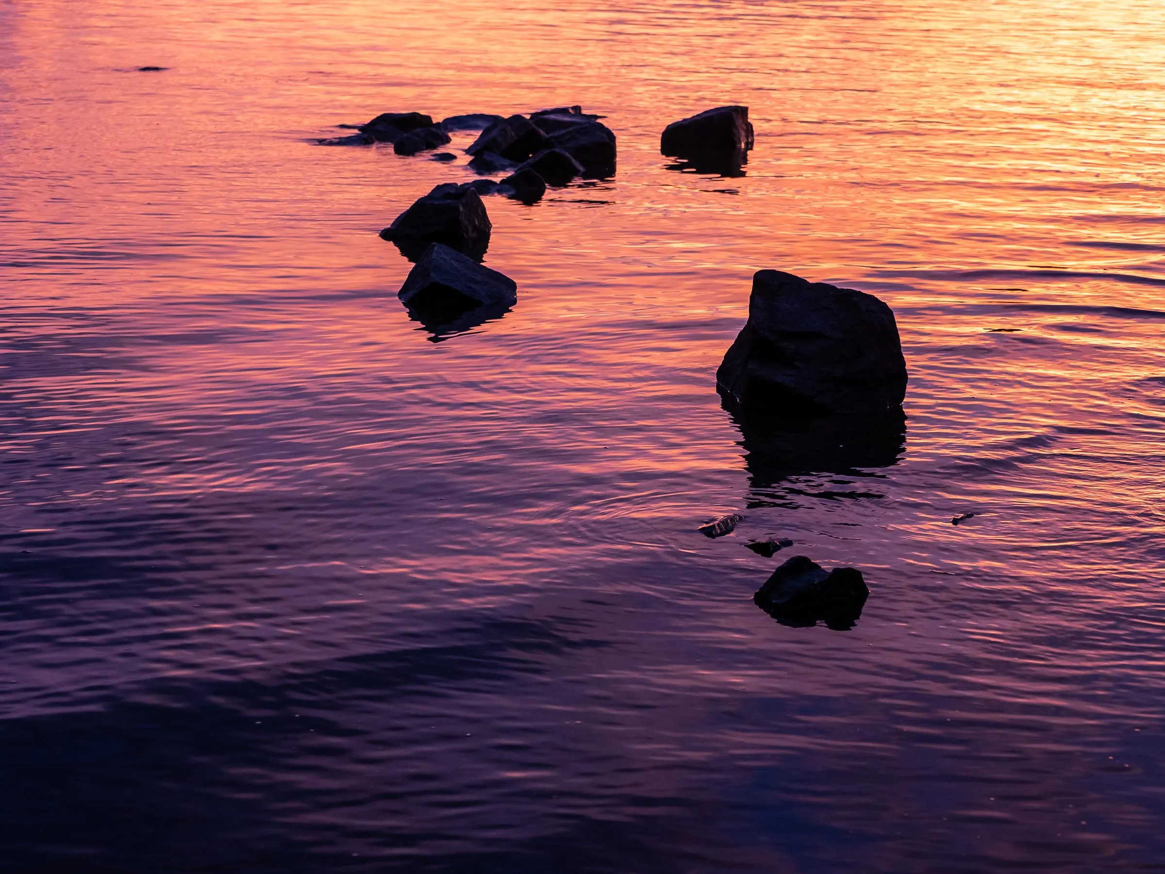 Dark stones in violet water at dusk