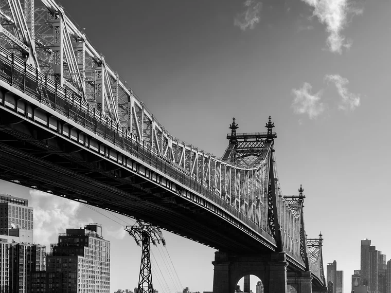 Black-and-white bridge and cityscape, repeating turrets receding into the distance with a single soft cloud above the rigid geometry.
